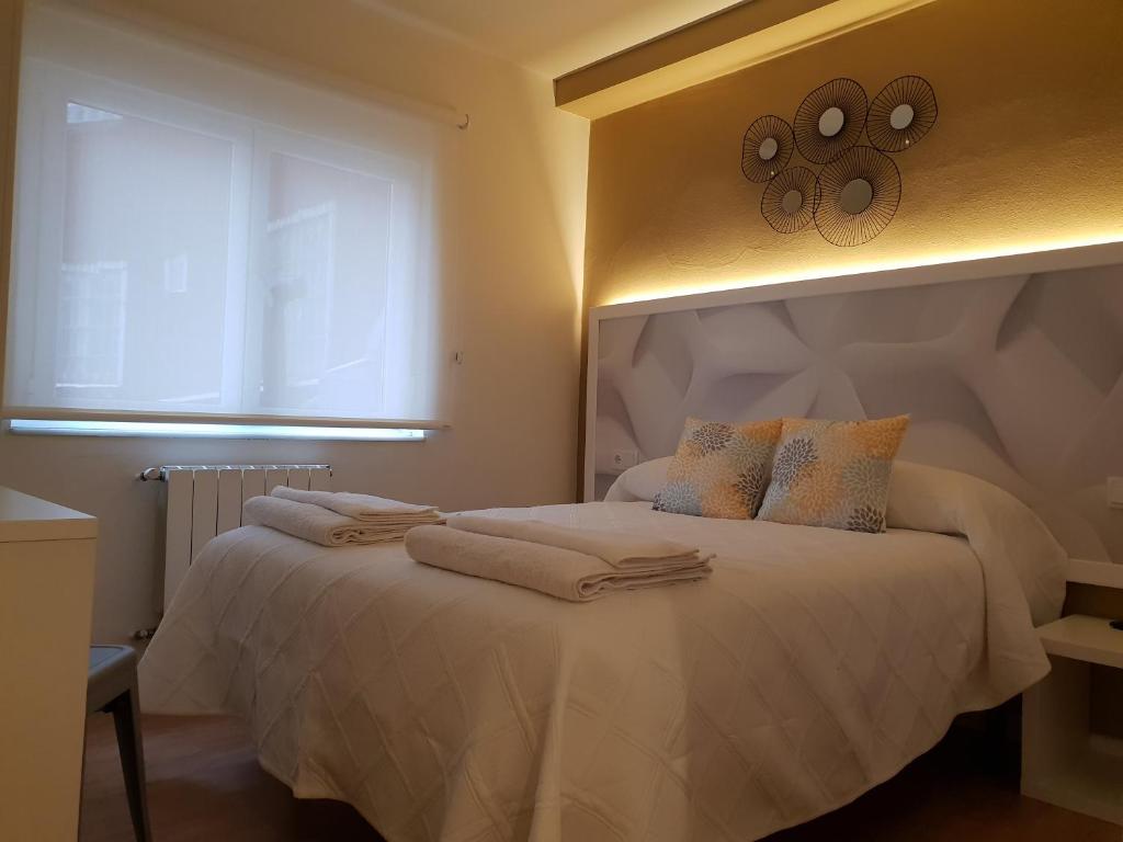 um quarto com uma cama com toalhas em Pensión Cabezas em Lugones