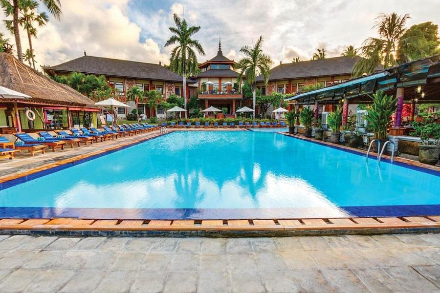 a pool at a resort with chairs and a building at Cozy Bali Apartment in Seminyak