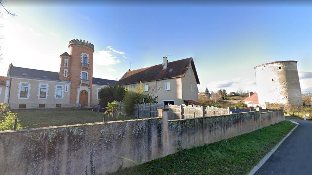 ein großes Haus mit einem Turm und einer Wand in der Unterkunft Maison indépendante, domaine VICHY LA TOUR in Abrest