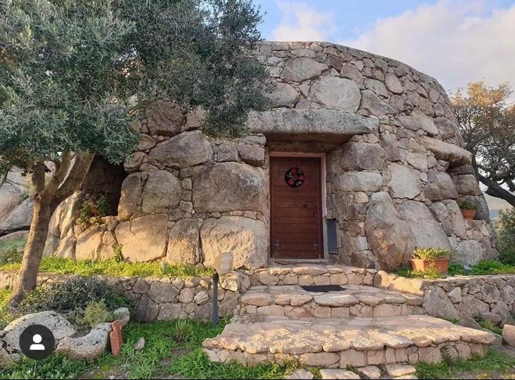 a small stone house with a door and a tree at Il Nuraghe del lago Coghinas in Oschiri