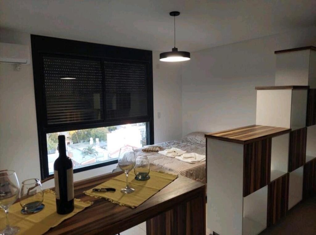 um quarto com uma mesa com copos de vinho e uma janela em Alquiler temporario Rosario em Rosário
