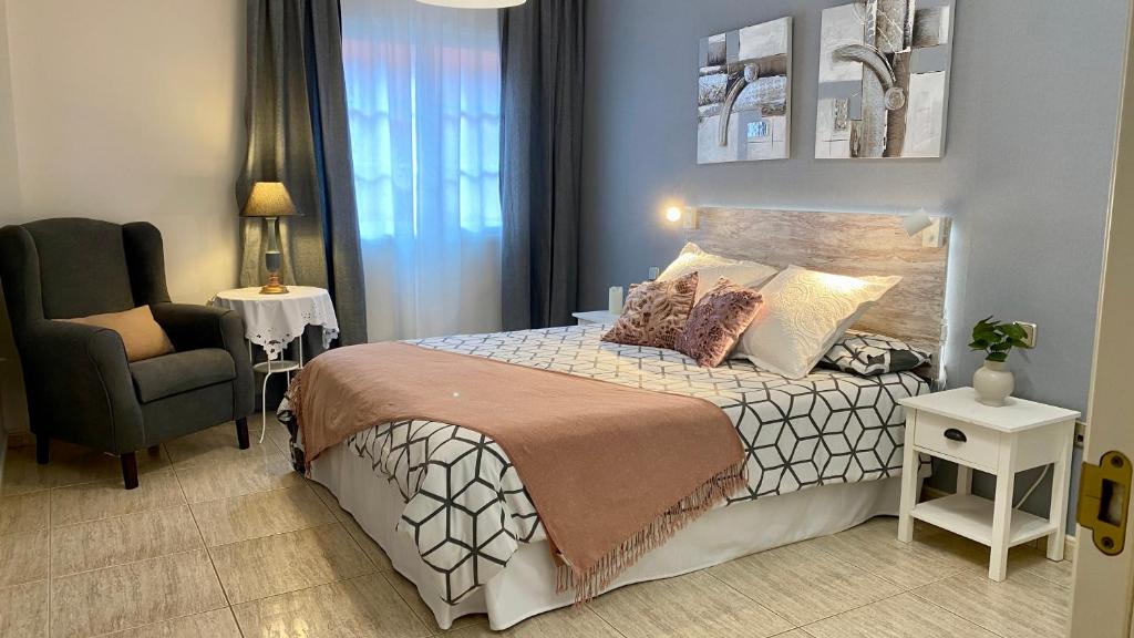 een kleine slaapkamer met een bed en een stoel bij Elegante piso en Puerto de la Cruz in Puerto de la Cruz