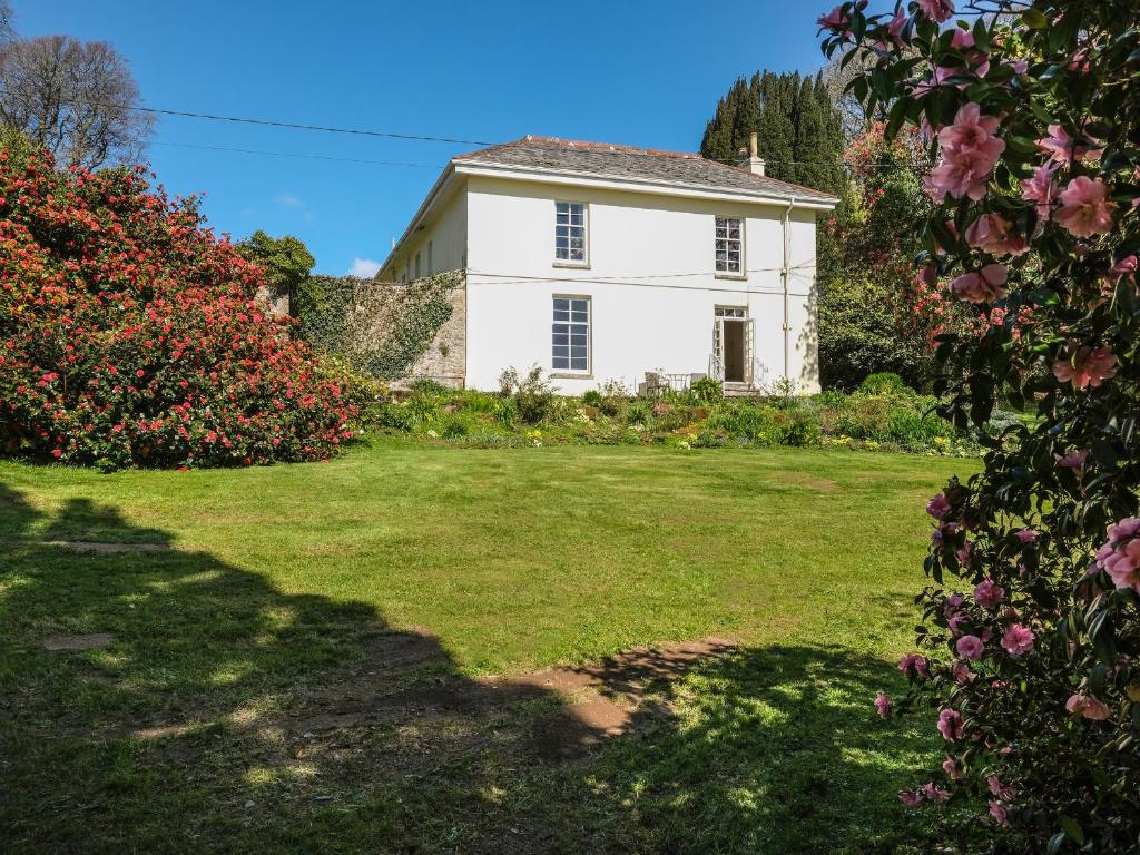 a white house with a yard with flowers at The Patio Flat in Bodmin