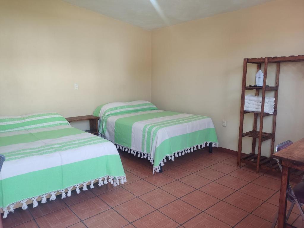 une chambre avec deux lits et une étagère dans l'établissement Casa Cora Oaxaca Hospedaje Familiar Guesthouse Casa de Huespedes, à Oaxaca