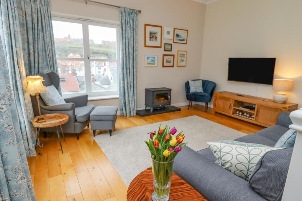 ein Wohnzimmer mit Sofa und Fernseher in der Unterkunft Grays Cottage in Whitby