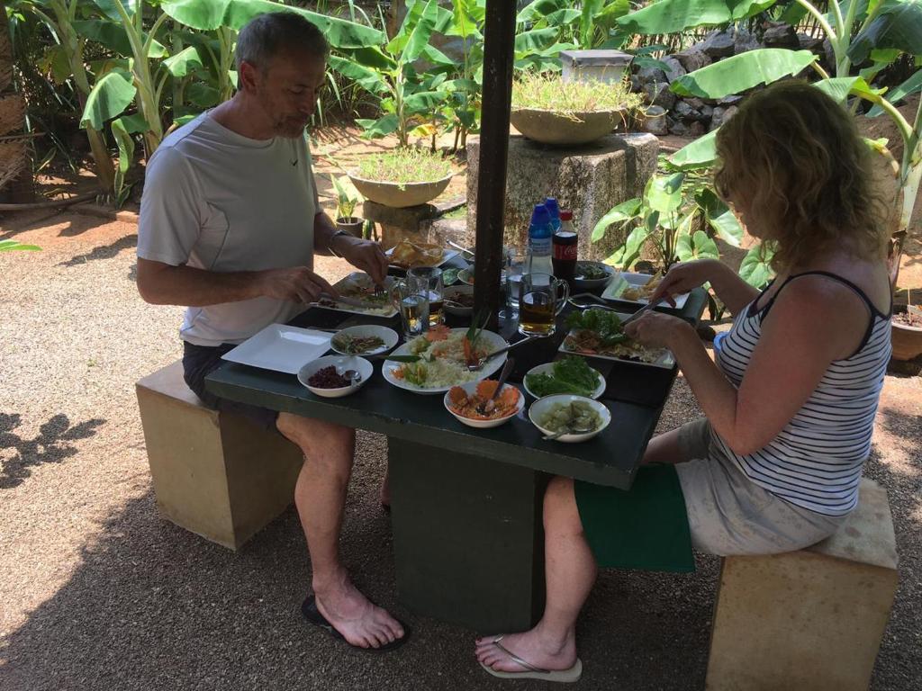 Um homem e uma mulher sentados à mesa com comida. em Chandi Relax Hostel em Sigiriya