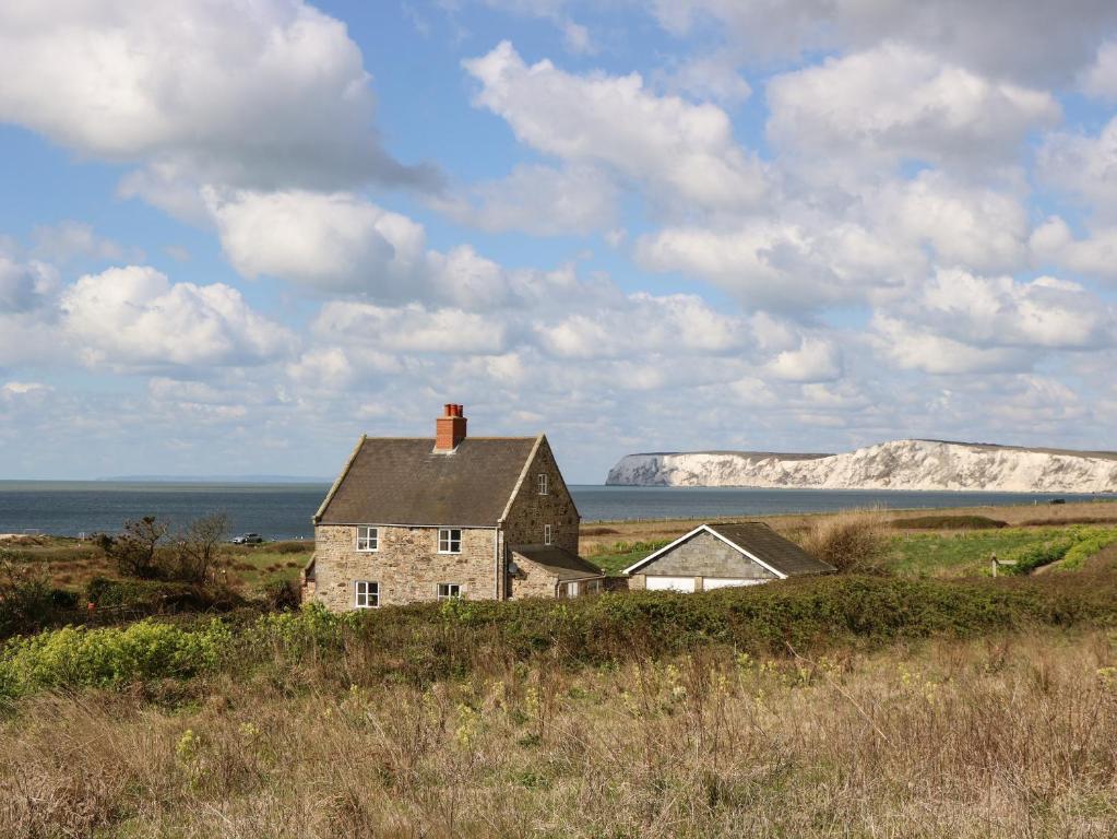 an old house on the beach with cliffs in the background at Compton Grange in Newport
