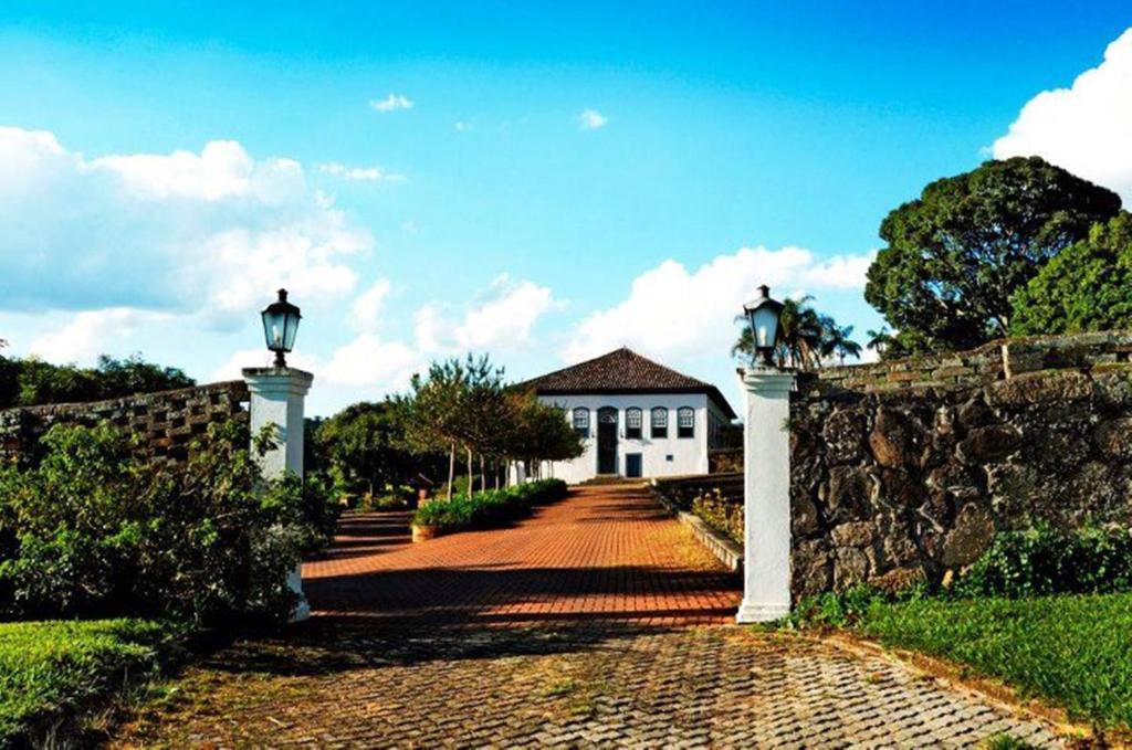 a gate to a white house with a stone wall at Hotel Fazenda Dona Carolina in Itatiba