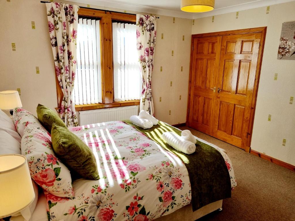 a bedroom with a bed with a floral bedspread at Inverness City 3 bedroom house in Inverness