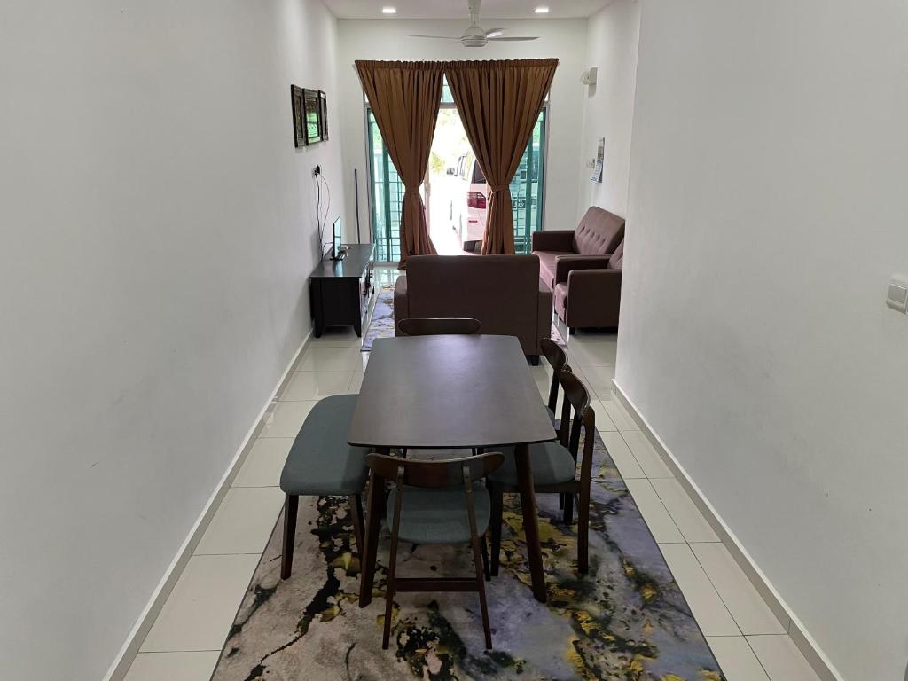 a dining room with a table and chairs on a rug at Maryam Homestay in Jertih