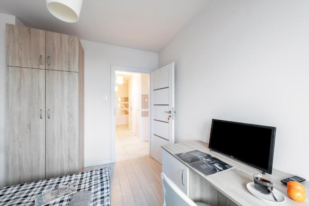 a living room with a tv and a tv stand in a room at Pokoje Wita Stwosza in Warsaw