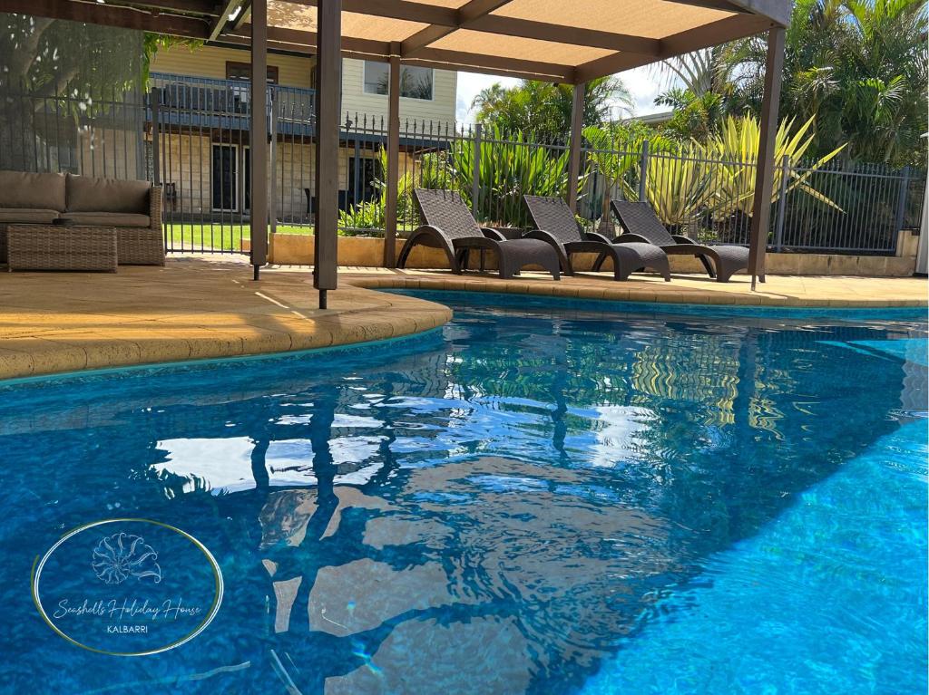 - une piscine avec des chaises à côté d'une maison dans l'établissement Seashells Holiday House - Kalbarri, à Kalbarri