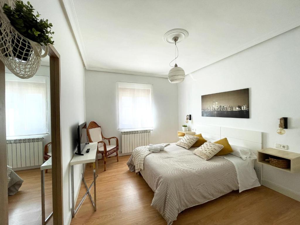 a white bedroom with a bed and a desk at LORE - Parking y bicis gratis in San Sebastián