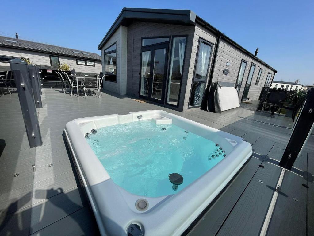 a hot tub on the deck of a house at Indulgence Lakeside Lodge i3 with hot tub, private fishing peg situated at Tattershall Lakes Country Park in Tattershall