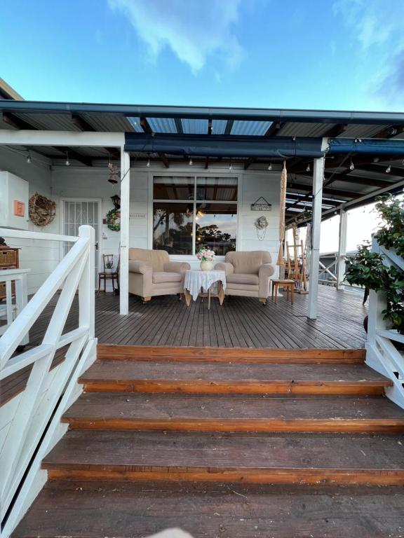 a deck with a couch and table on a house at Ivy May Cottage in Lakes Entrance