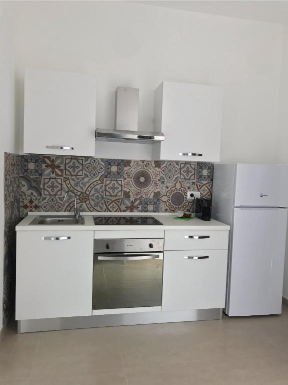 Biała kuchnia z kuchenką i lodówką w obiekcie Casa via Garibaldi w mieście Leverano