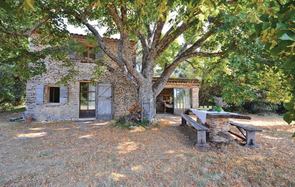 ein Steingebäude mit zwei Bänken vor einem Baum in der Unterkunft Cozy Home In Saignon With Kitchen in Saignon
