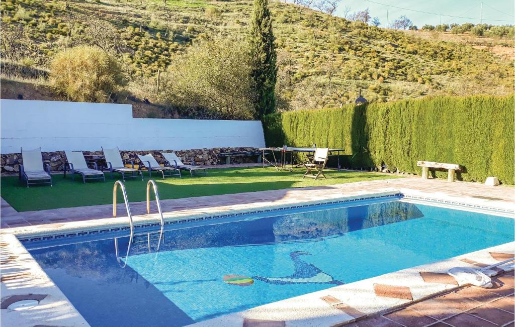 een zwembad in een tuin met stoelen en een tafel bij 3 Bedroom Pet Friendly Home In Villanueva De La Conc, in La Joya
