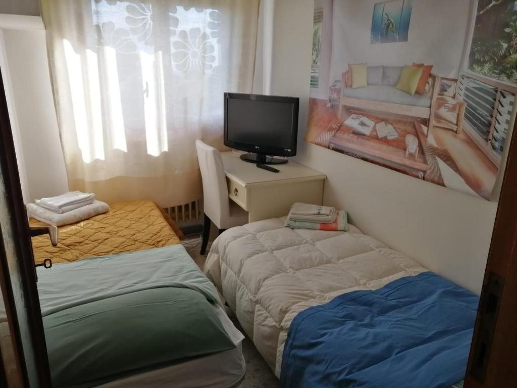 mały pokój z 2 łóżkami i telewizorem w obiekcie Casa Giardino sul Mare w mieście Grottammare