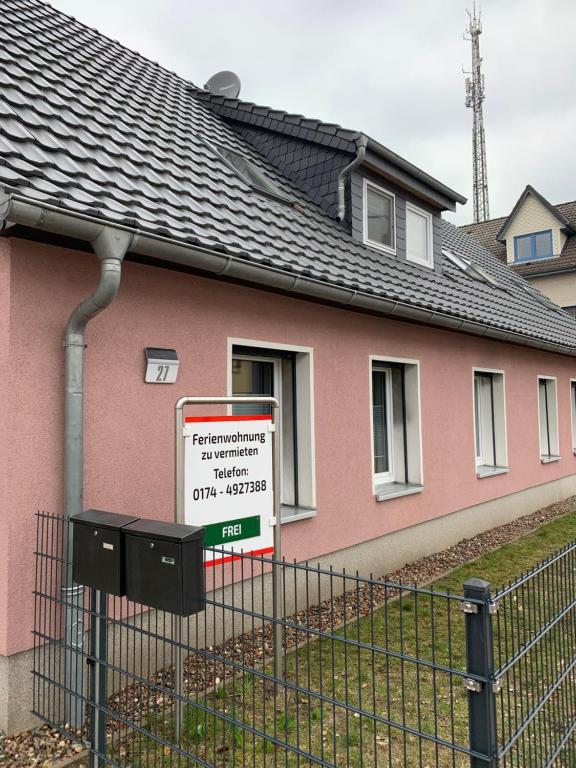 a sign in front of a pink house at Ferienwohnung Alois in Ueckermünde