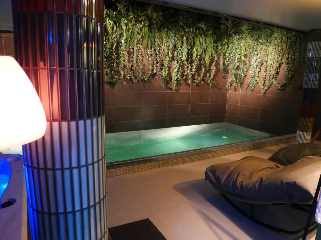 a swimming pool in a room with a bed next to it at Nocturnal Spa Package Midnight to Noon in Coubron