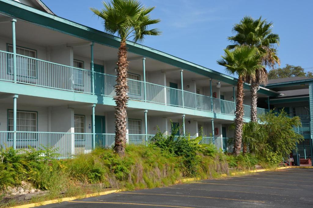 een lege parkeerplaats voor een hotel met palmbomen bij Stay Express Inn Near Ft. Sam Houston in San Antonio