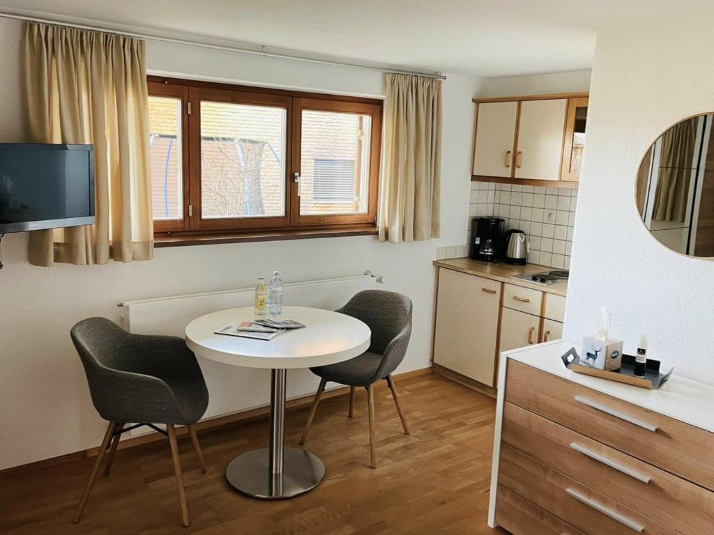 uma pequena cozinha com uma mesa branca e cadeiras em Ferienwohnung Geismayr em Dornbirn