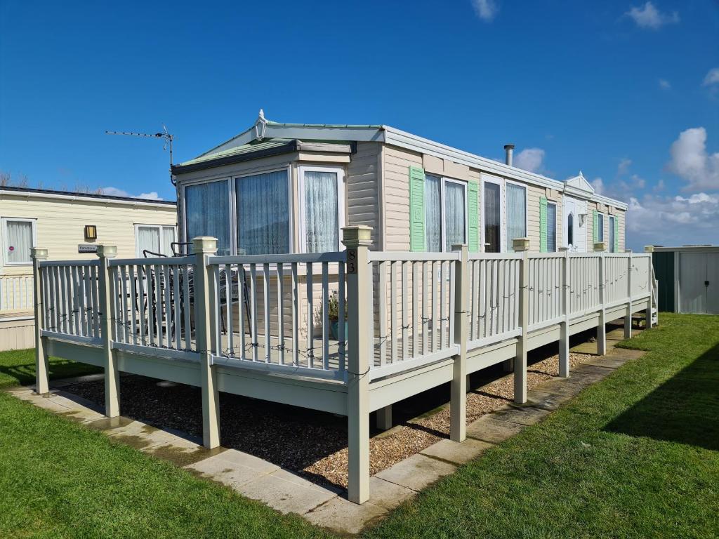 uma casa móvel num deque com uma cerca em 6 berth Trusthorpe Springs (Mayfair) em Sutton-on-Sea