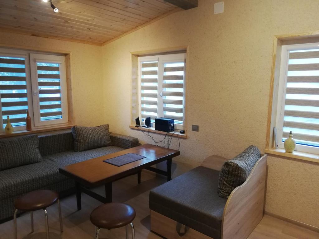 uma sala de estar com um sofá, uma mesa e janelas em Butas su sodu saulėtoje verandoje Juodkrantėje, prie Ievos Kalno em Juodkrantė