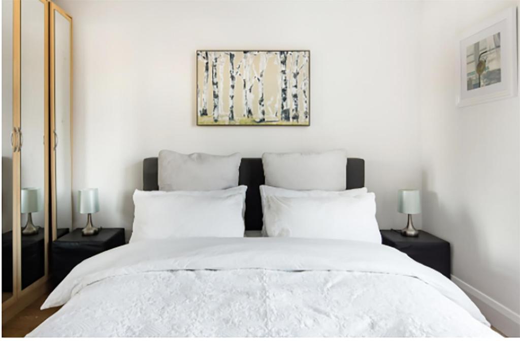 倫敦的住宿－絕美伊斯特芬奇利公寓，一间卧室配有一张带两盏灯的大型白色床。