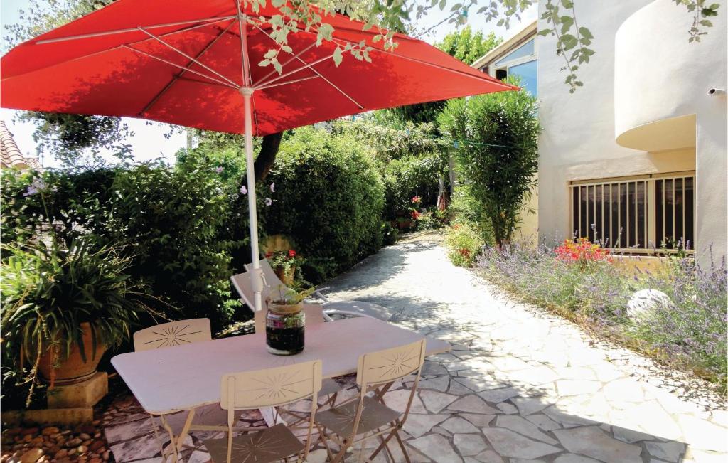 a table with a red umbrella on a patio at Stunning Apartment In Pignan With Kitchen in Pignan