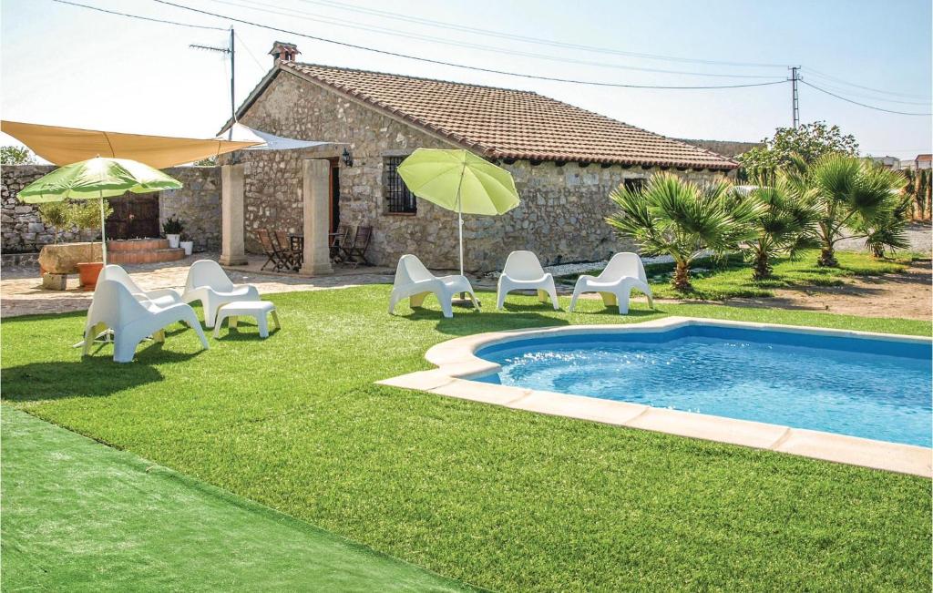 una piscina con sillas y sombrillas en un patio en Gorgeous Home In Villanueva Del Duque With Wifi, en Villanueva del Duque