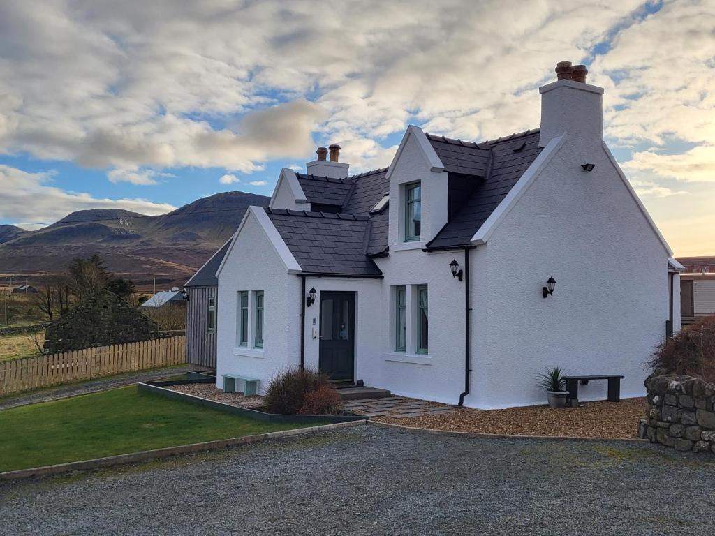 a white house with mountains in the background at An Cnoc Bed & Breakfast in Staffin