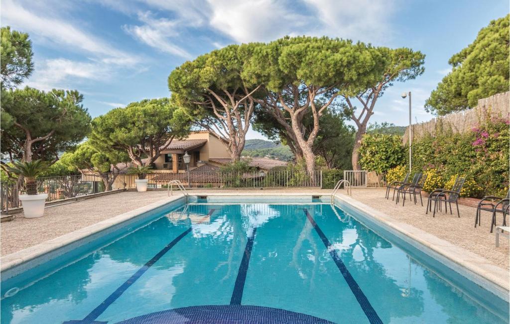 uma piscina azul com cadeiras e árvores em Amazing Home In Cabrils With 4 Bedrooms, Wifi And Outdoor Swimming Pool em Cambrils
