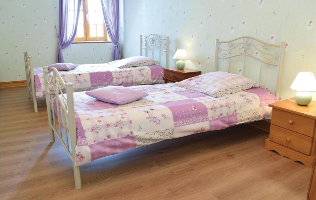 two beds in a bedroom with purple walls and wooden floors at Nice Home In Canchy With Kitchen in Canchy