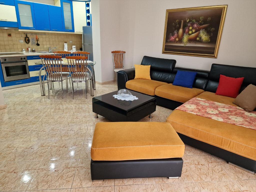 uma sala de estar com sofás e uma mesa e uma cozinha em Apartament Orion em Vlorë