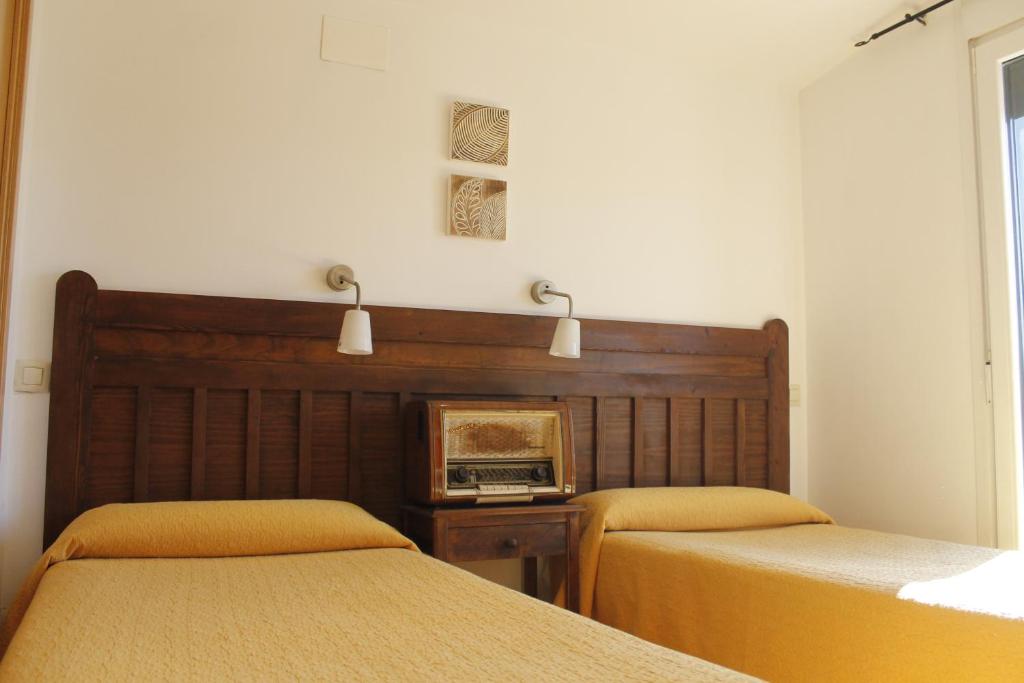 1 dormitorio con 2 camas y reloj en la pared en Hostal Restaurante Bustos, en Villarrubio