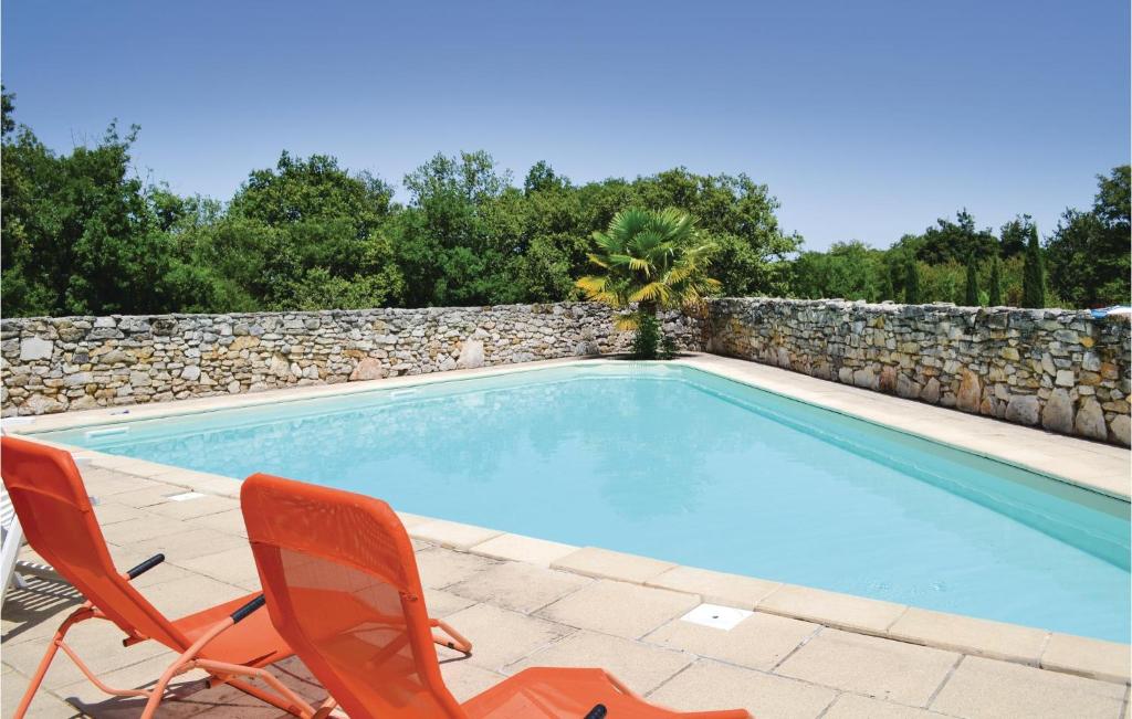 a swimming pool with two chairs and a stone wall at 2 Bedroom Awesome Home In Padirac in Padirac