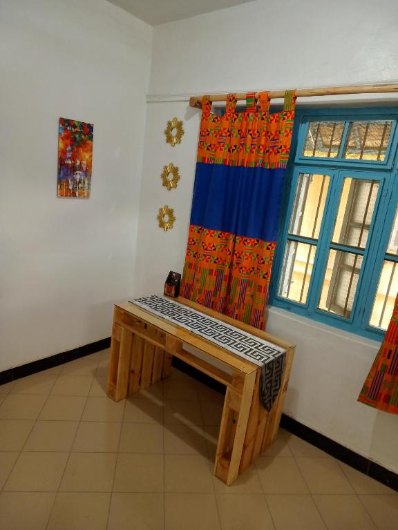 un banco de madera en una habitación con ventana en Karibu Nyumbani, Welcome Home en Mwanza