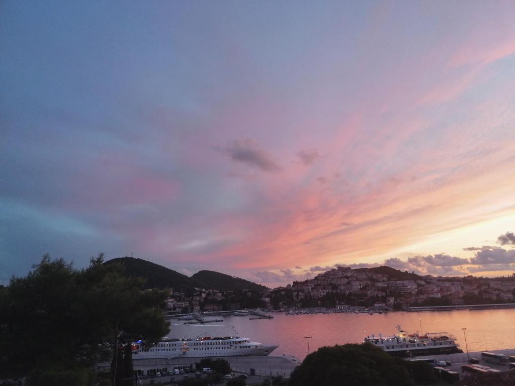 a sunset over a harbor with two boats in the water at Apartments Grebović in Dubrovnik