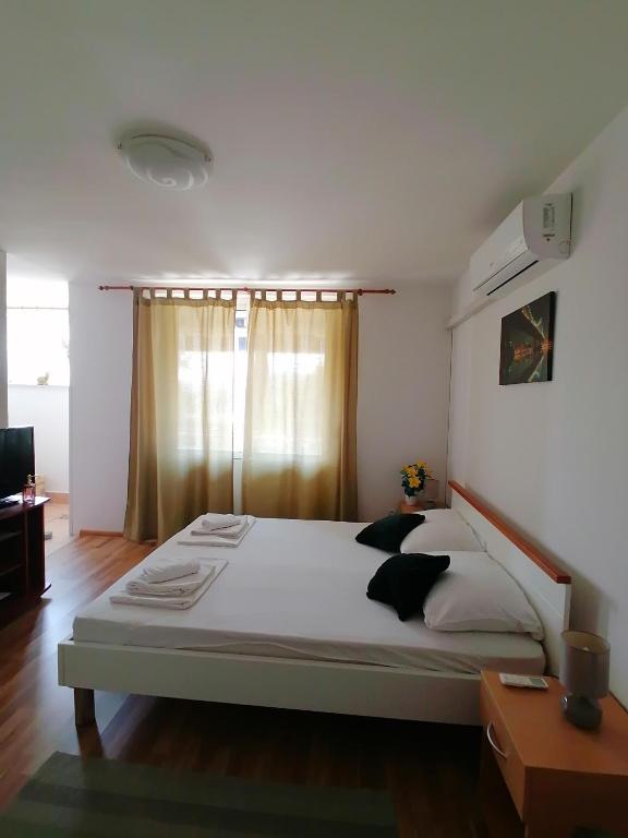 a bedroom with a large bed with white sheets and black pillows at Apartments Grebović in Dubrovnik