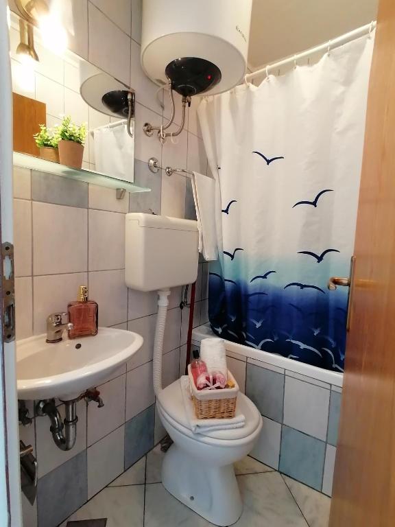 a bathroom with a toilet and a sink and a shower curtain at Apartments Grebović in Dubrovnik