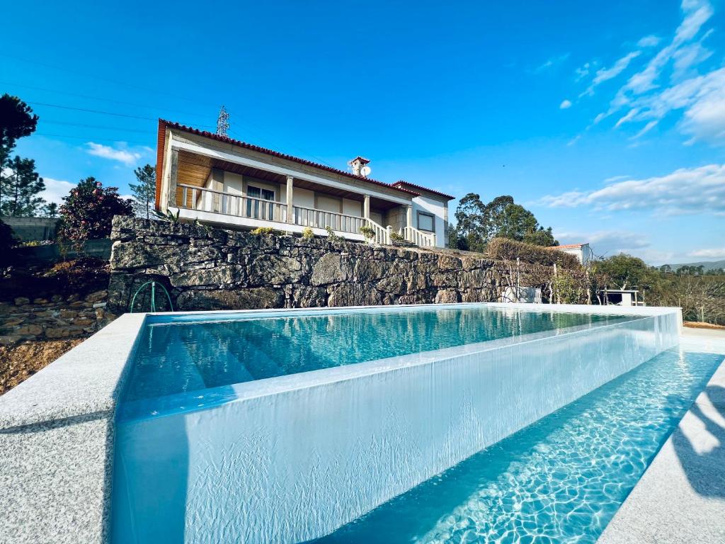 ein Schwimmbad mit einem Haus im Hintergrund in der Unterkunft Cerdeirinhas de basto Hospedagem in Canedo de Basto