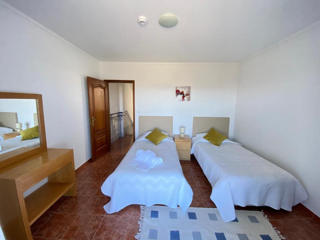 ein Schlafzimmer mit zwei Betten und einem Spiegel in der Unterkunft Ericeira Sand Beach F7 in Ericeira
