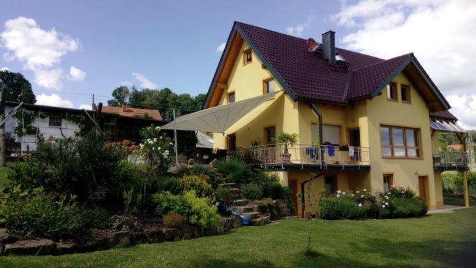 una gran casa amarilla con un patio ajardinado en Ferienwohnung Maintalblick, en Mainleus