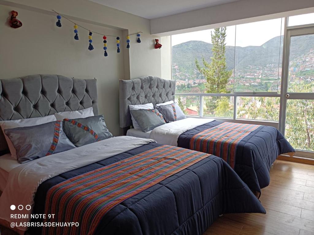 a bedroom with two beds and a large window at Union Garden Apartments in Cusco