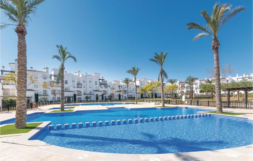 a swimming pool with palm trees and buildings in the background at 2 Bedroom Amazing Apartment In Roldán in Los Tomases