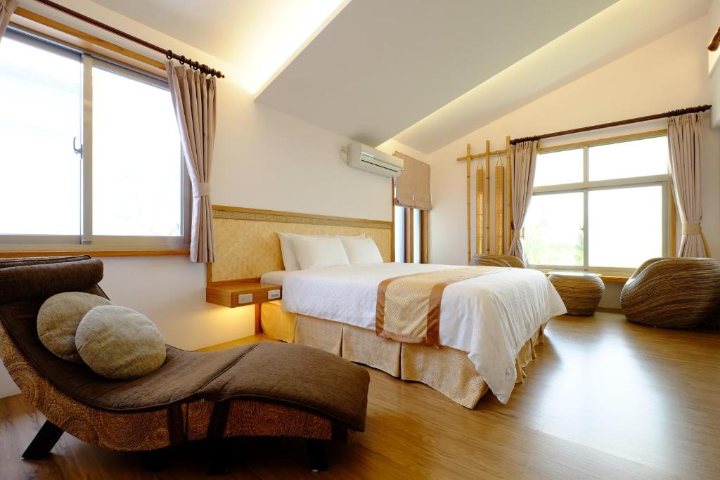 a bedroom with a bed and a chair and windows at Cloud Inn in Hengchun South Gate