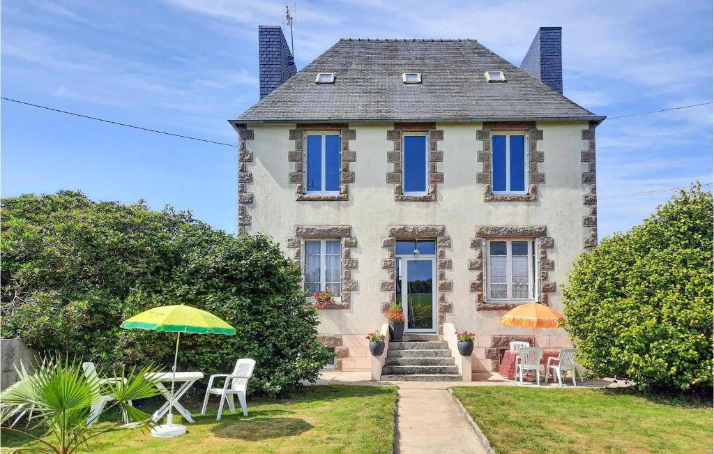 a house with chairs and umbrellas in front of it at Awesome Home In Morlaix With 3 Bedrooms in Sainte-Geneviève