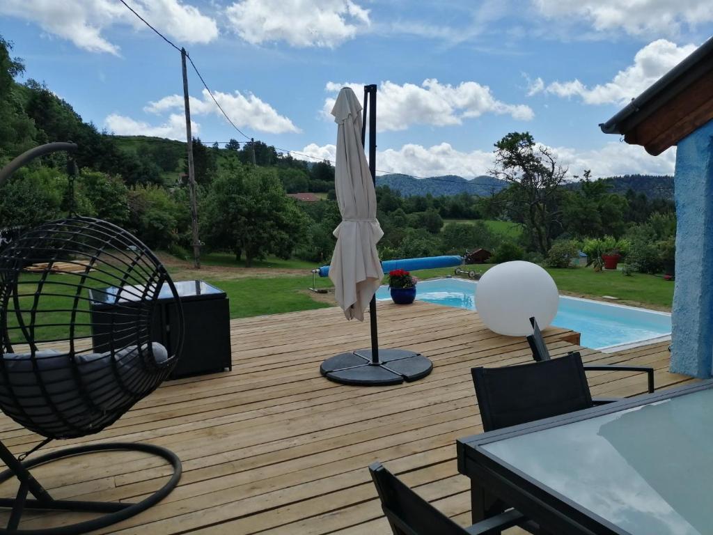 una terraza con sombrilla, sillas y piscina en La maison bleue, en Altenbach